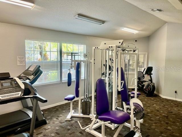 workout area featuring dark carpet and a textured ceiling