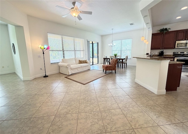 unfurnished living room featuring light tile patterned floors, ceiling fan with notable chandelier, and sink