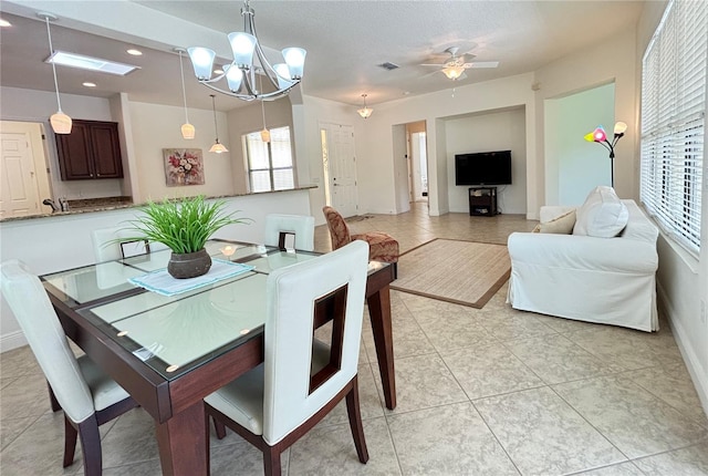 dining space with a textured ceiling, light tile patterned flooring, and ceiling fan with notable chandelier