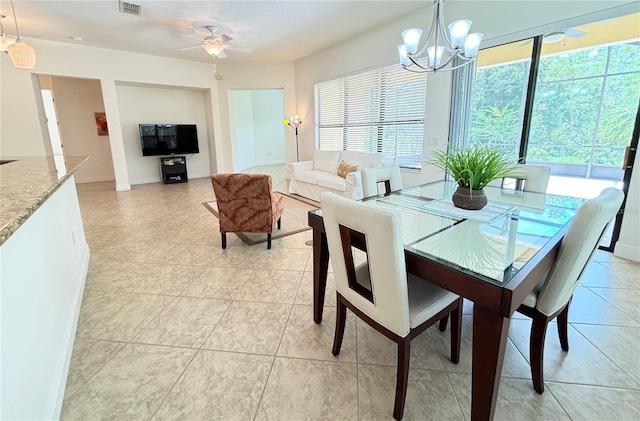 tiled dining area featuring ceiling fan with notable chandelier