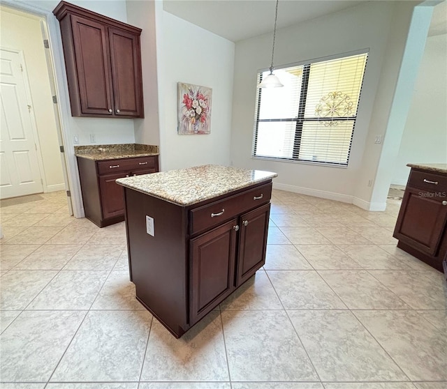 kitchen with light tile patterned floors, dark brown cabinetry, decorative light fixtures, and a kitchen island