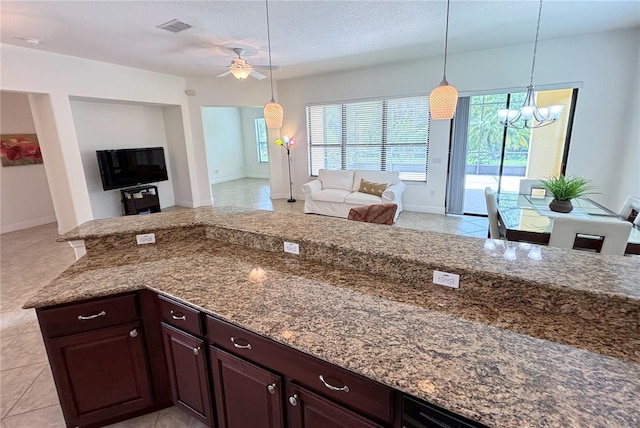 kitchen featuring a textured ceiling, ceiling fan with notable chandelier, stone countertops, and decorative light fixtures