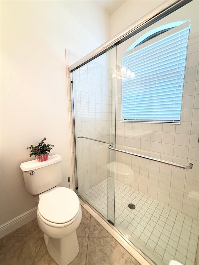 bathroom with tile patterned flooring, toilet, and a shower with shower door