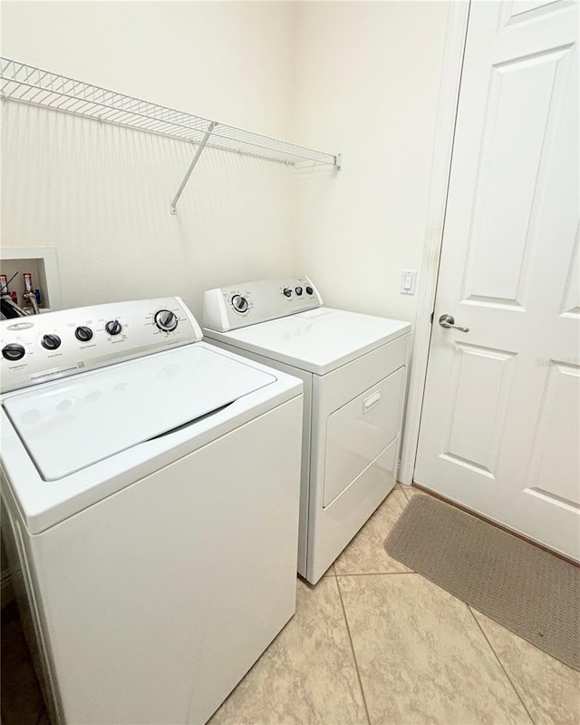 clothes washing area with washer and clothes dryer and light tile patterned floors