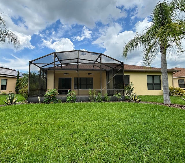 back of house featuring ceiling fan, a lanai, and a yard