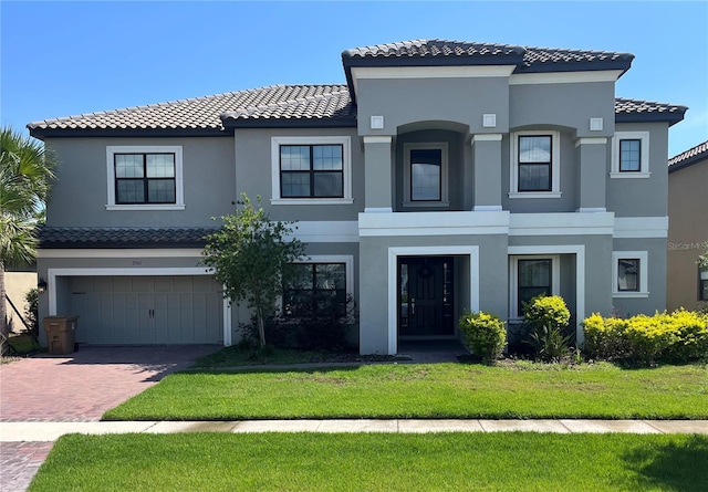 mediterranean / spanish home featuring a front yard and a garage