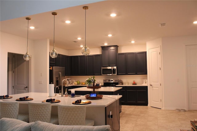 kitchen featuring sink, an island with sink, hanging light fixtures, and appliances with stainless steel finishes