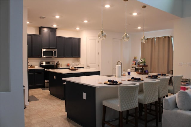 kitchen with pendant lighting, a kitchen island with sink, sink, a kitchen bar, and stainless steel appliances