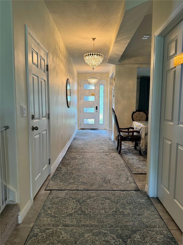 hallway featuring an inviting chandelier and a textured ceiling