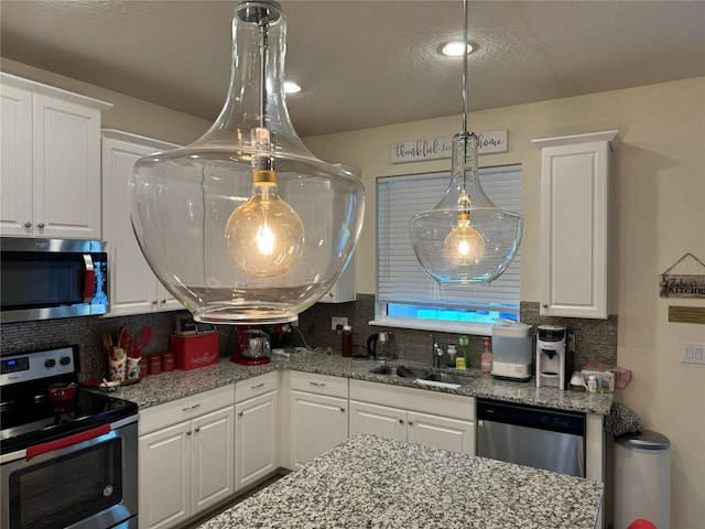 kitchen with appliances with stainless steel finishes, tasteful backsplash, sink, and white cabinets