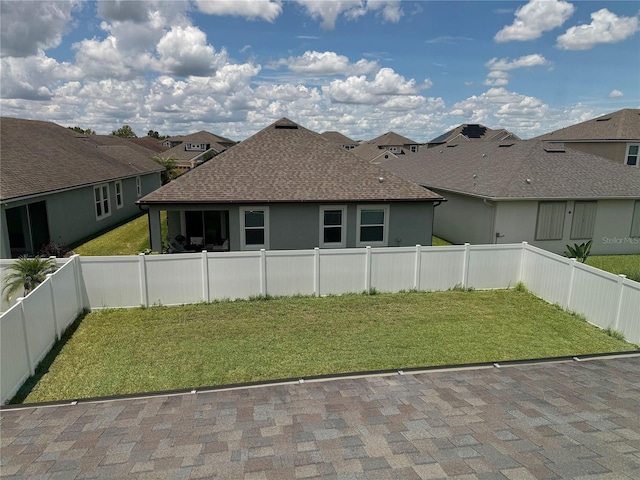 rear view of house featuring a lawn and a patio