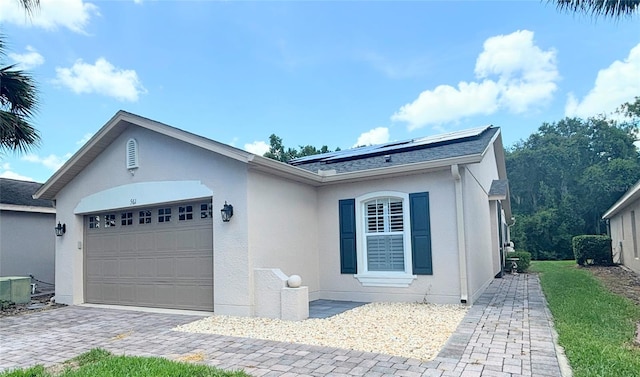 single story home with solar panels and a garage