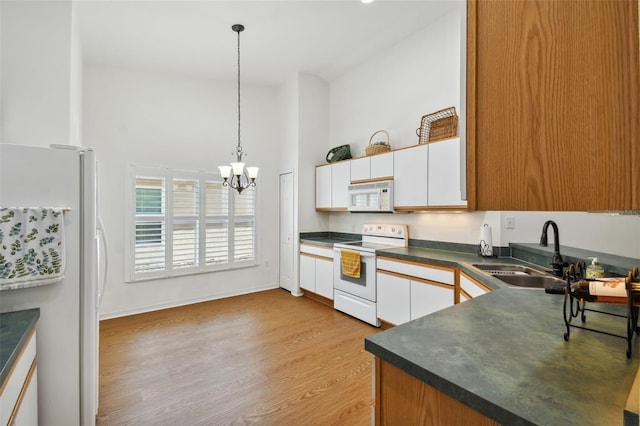 kitchen with white cabinetry, sink, a chandelier, white appliances, and decorative light fixtures