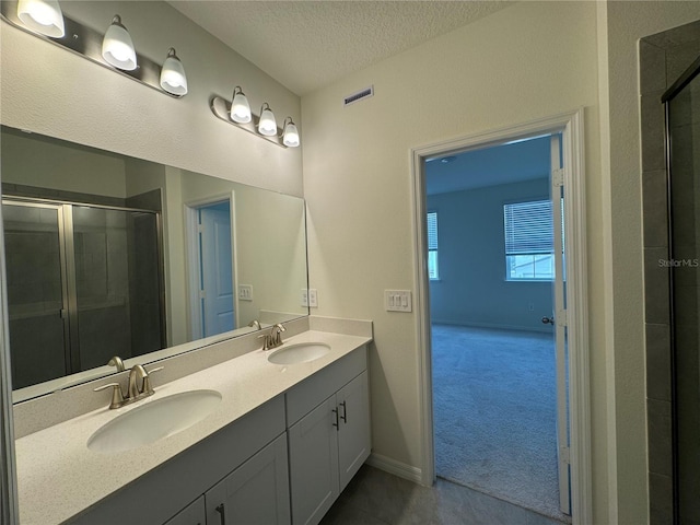 bathroom featuring vanity, an enclosed shower, and a textured ceiling