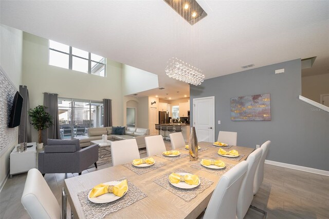 dining area featuring an inviting chandelier, tile patterned flooring, and a towering ceiling