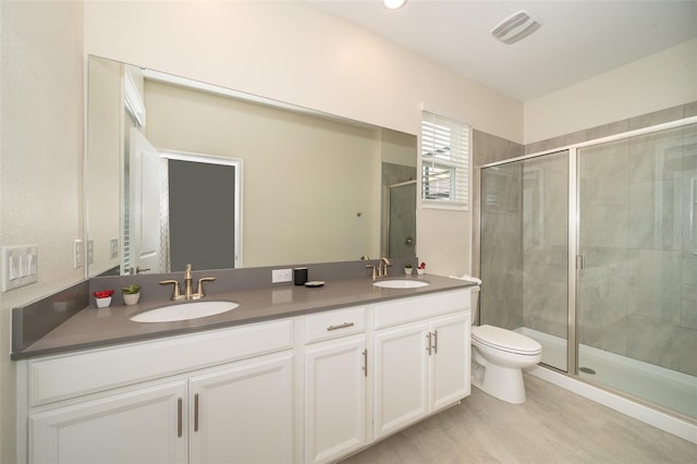 bathroom with toilet, walk in shower, and dual bowl vanity