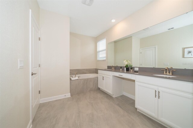 bathroom featuring tiled bath and double sink vanity