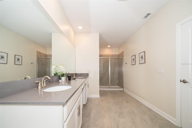 bathroom featuring an enclosed shower and double vanity