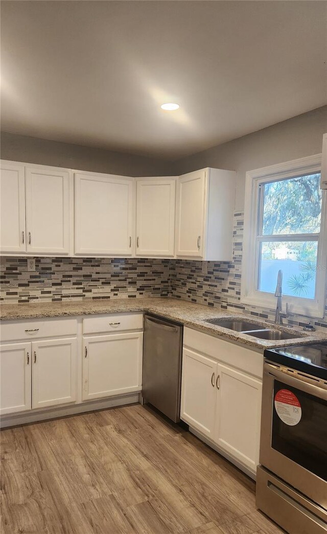 kitchen featuring white cabinetry, stainless steel appliances, decorative backsplash, and light wood-type flooring