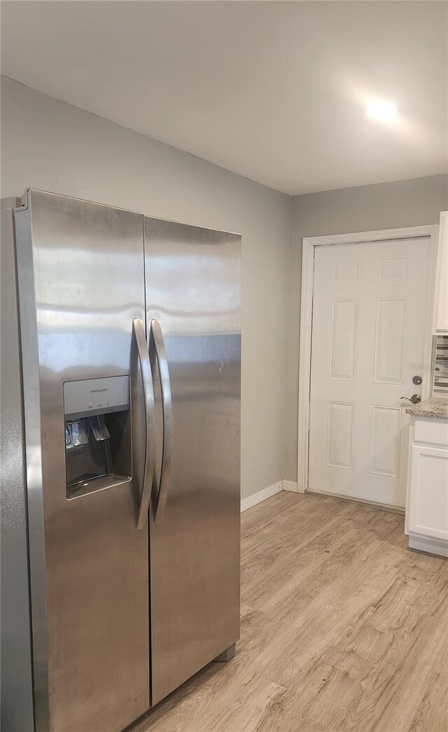 kitchen featuring light hardwood / wood-style flooring, white cabinets, and stainless steel fridge