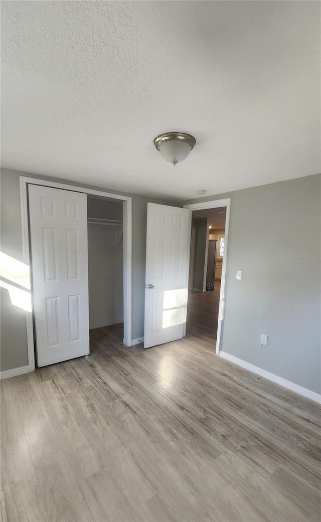 unfurnished bedroom featuring a closet, a textured ceiling, and hardwood / wood-style flooring