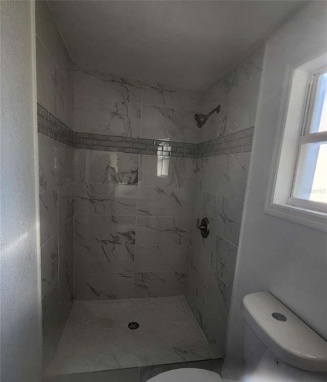 bathroom featuring a tile shower and toilet