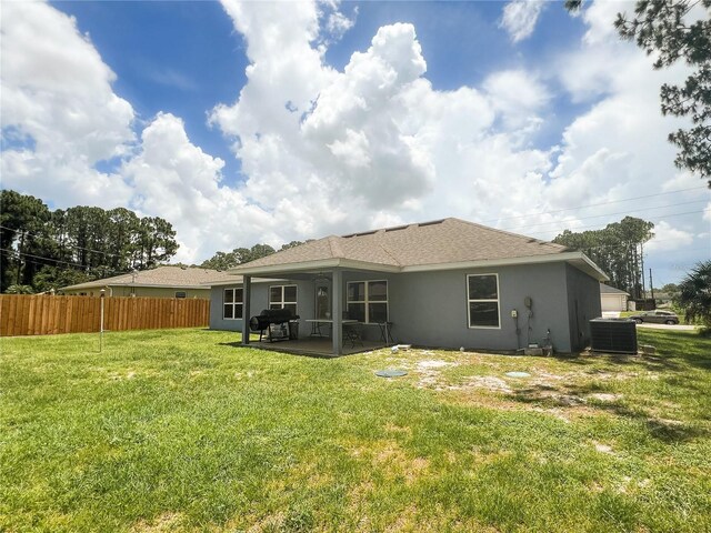 rear view of property with a patio, central AC, and a lawn