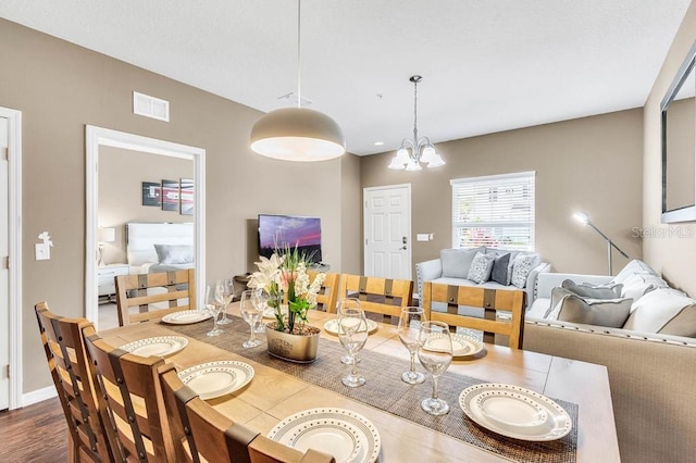 dining area with dark wood-style floors, visible vents, and a chandelier