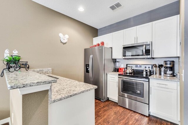 kitchen featuring dark hardwood / wood-style floors, stainless steel appliances, white cabinetry, and light stone counters