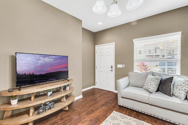 living room with an inviting chandelier, baseboards, and wood finished floors