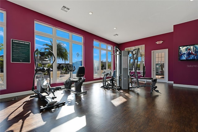 workout area featuring baseboards, visible vents, and wood finished floors