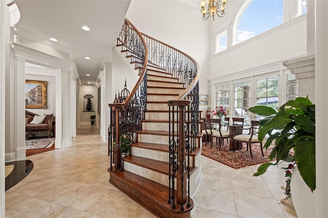 tiled entryway featuring a high ceiling and a notable chandelier