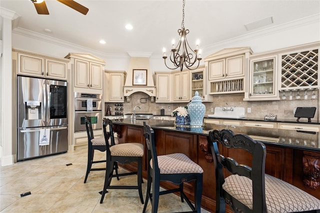 kitchen with stainless steel appliances, decorative light fixtures, a kitchen bar, and cream cabinetry