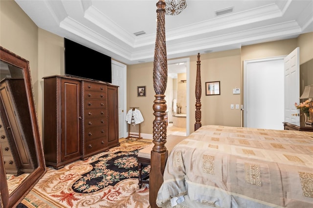 bedroom featuring ornamental molding, ensuite bathroom, and a tray ceiling