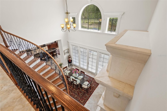 staircase with an inviting chandelier, tile patterned floors, and a high ceiling