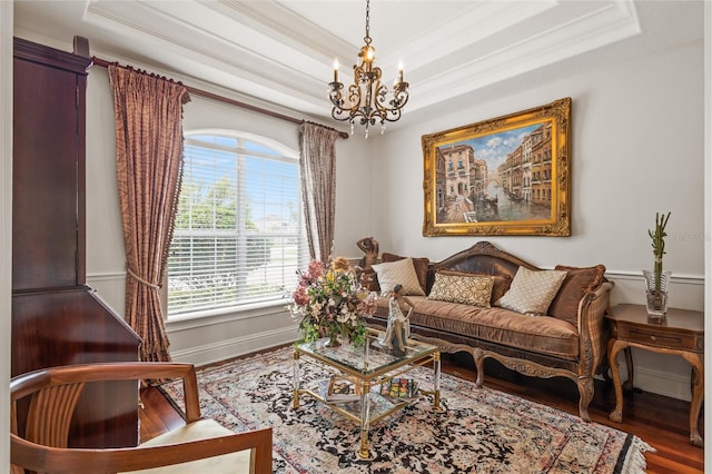 living room featuring hardwood / wood-style floors, crown molding, a raised ceiling, and a chandelier