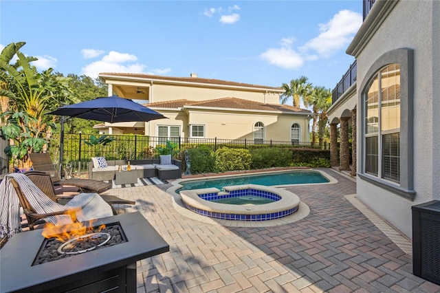 view of patio with a swimming pool with hot tub and a fire pit