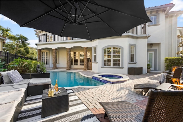 view of pool with a patio, an in ground hot tub, and an outdoor living space with a fire pit