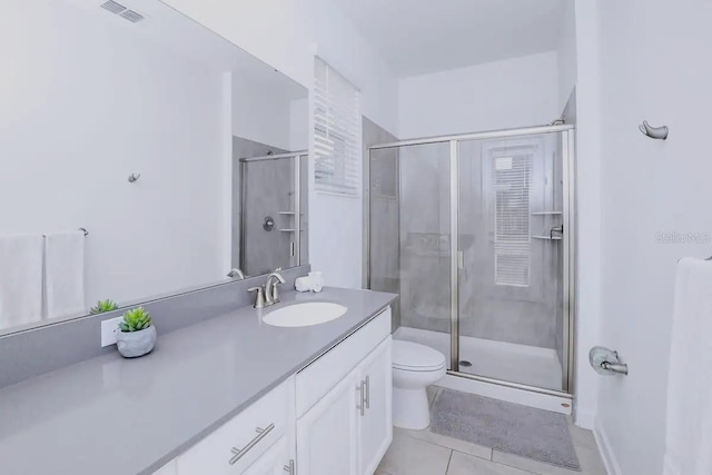 bathroom with toilet, vanity, tile patterned floors, and walk in shower