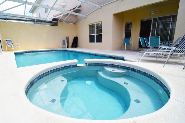 view of pool with an in ground hot tub, ceiling fan, and glass enclosure