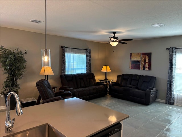 tiled living room with a textured ceiling, ceiling fan, and sink