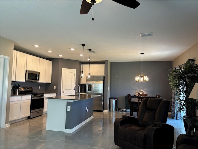 kitchen with a center island with sink, ceiling fan with notable chandelier, appliances with stainless steel finishes, and white cabinetry