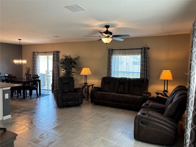 living room featuring ceiling fan with notable chandelier and a textured ceiling