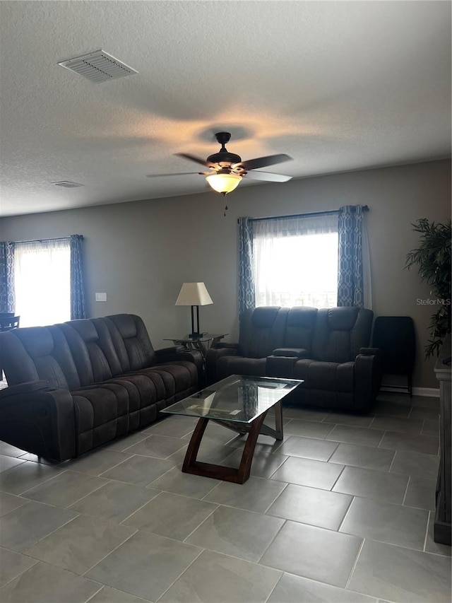 living room featuring ceiling fan, a wealth of natural light, and a textured ceiling