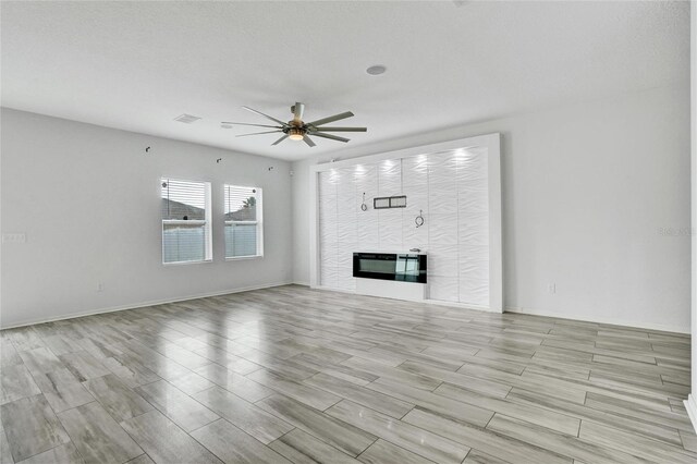 unfurnished living room featuring a textured ceiling, light wood-type flooring, and ceiling fan