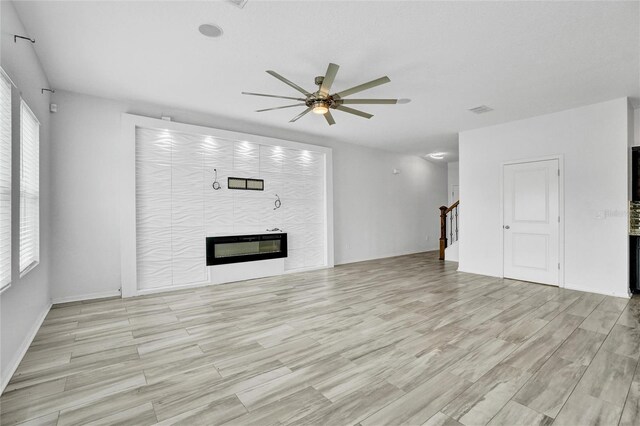 unfurnished living room featuring light hardwood / wood-style flooring, ceiling fan, and a tile fireplace