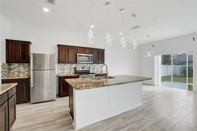 kitchen featuring light stone countertops, sink, pendant lighting, and appliances with stainless steel finishes