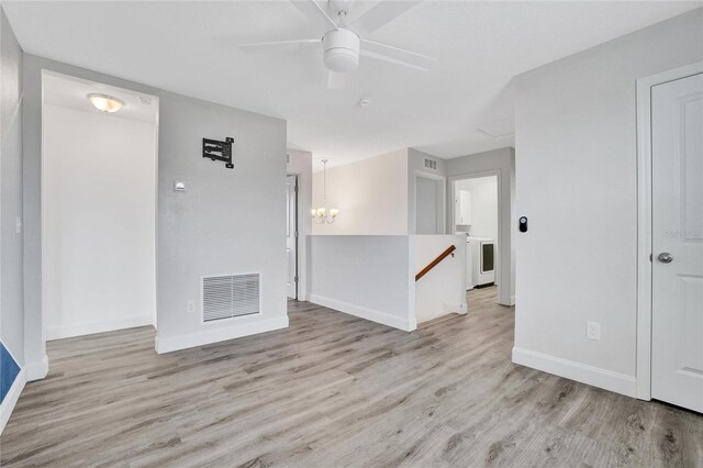 unfurnished room with ceiling fan with notable chandelier and light hardwood / wood-style flooring