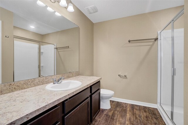 bathroom with vanity, hardwood / wood-style flooring, toilet, and a shower with shower door