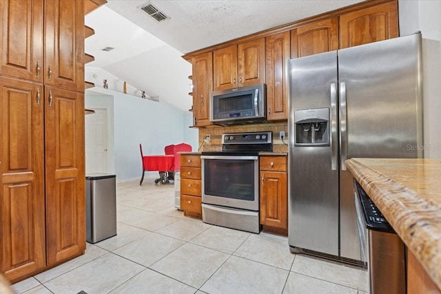 kitchen with light tile patterned flooring, stainless steel appliances, and vaulted ceiling